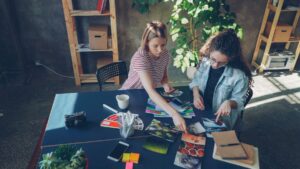 Two designers reviewing photographs and color swatches at a worktable.