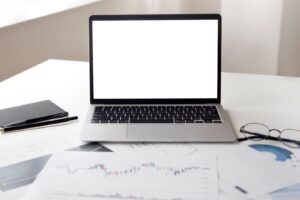 Laptop beside printed performance reports used to review ecommerce conversion tracking.