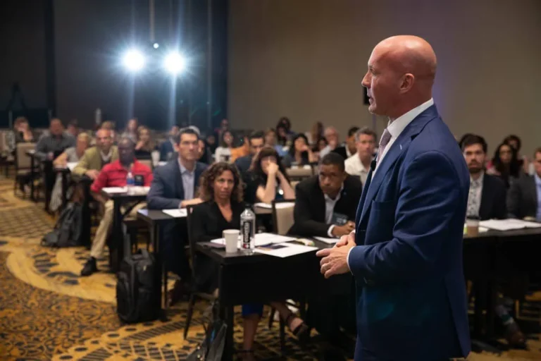 A Freedom Practice Coaching speaker addressing a seated audience at a workshop.