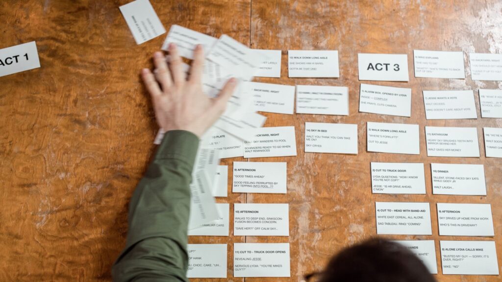 Hands arranging storyboard cards on a wooden table during creative planning