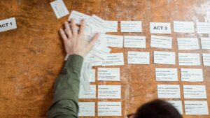 Hands arranging storyboard cards on a wooden table during creative planning