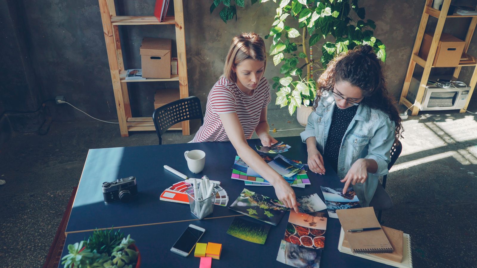 Two people reviewing printed photographs and color references at a table.