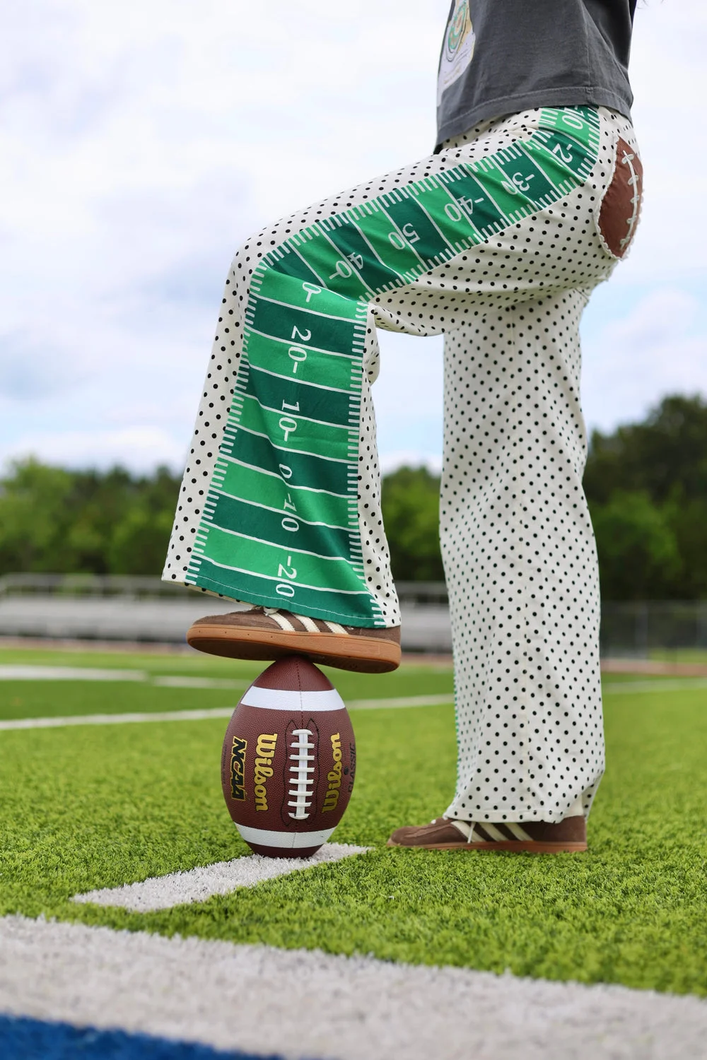 Poppy & Pine green and white printed wide-leg denim modeled beside a football.