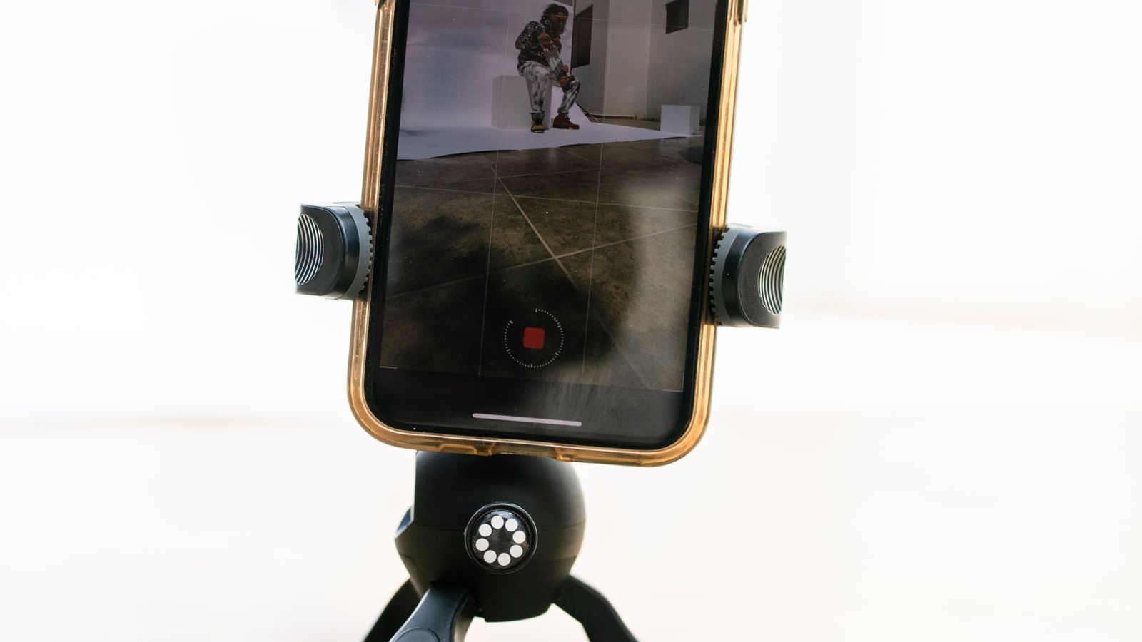 Smartphone mounted on a tripod recording video indoors.