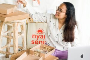 Small-business owner packing product orders beside a laptop.