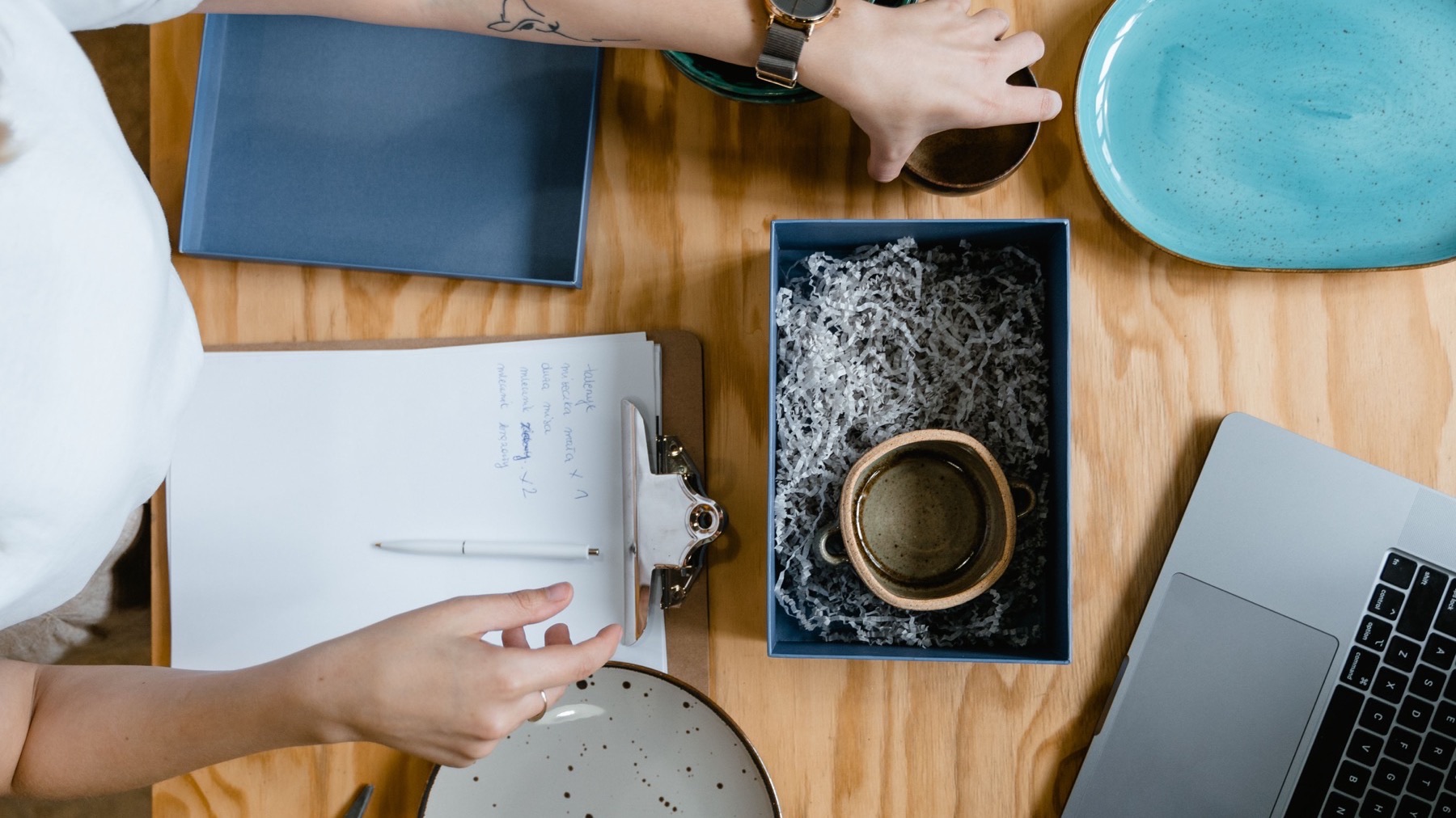 Overhead view of a seller packing a ceramic mug into a shipping box