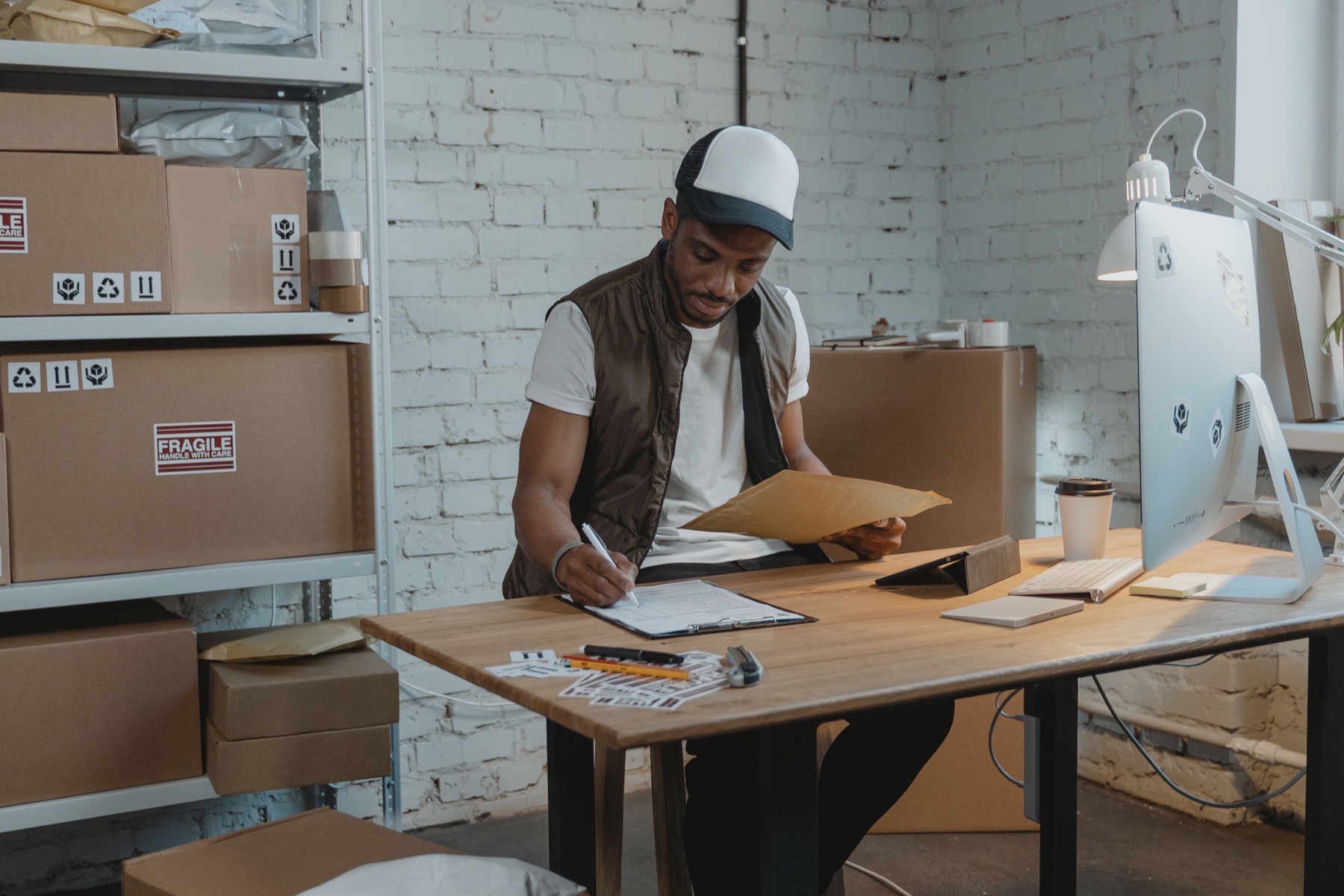 Warehouse employee reviewing shipment paperwork beside packed boxes.